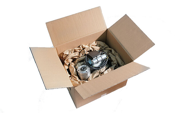 A cardboard box containing a technical device and paper cushioning