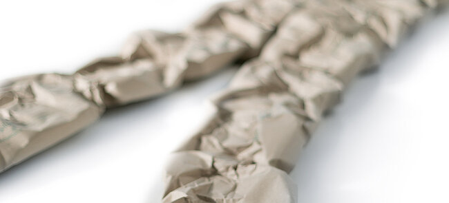
			Two paper cushioning strips made from grass paper