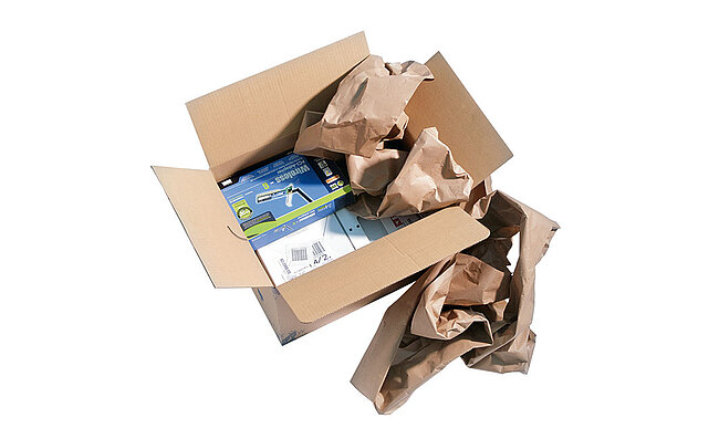 A cardboard box containing technical devices and brown paper cushioning
